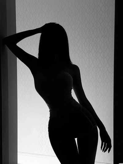 Silhouette of a woman posing with one hand on her head against a patterned background.