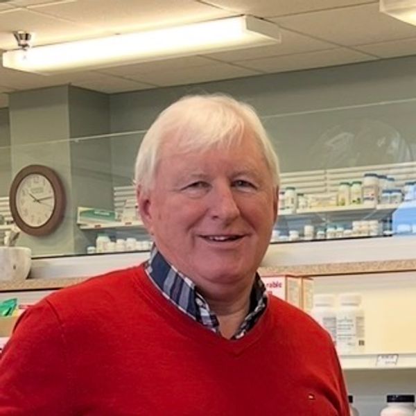 Smiling elderly man in red sweater at a pharmacy.