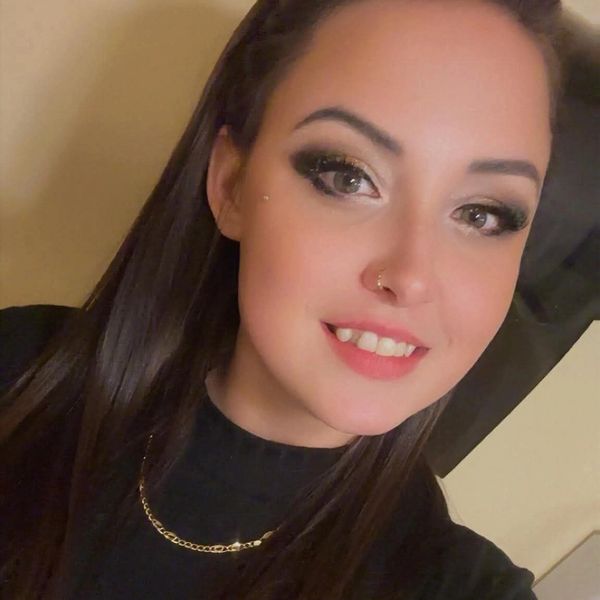 Young woman smiling with makeup and jewelry.