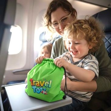 Child excitedly opening a green Travel Totz bag on an airplane with a smiling adult.