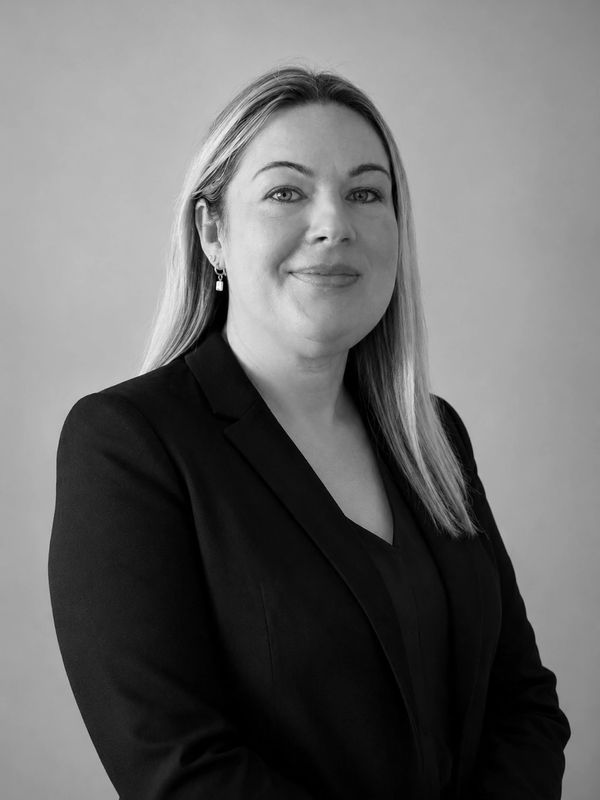 Professional black and white portrait of a woman in a blazer with a confident smile.