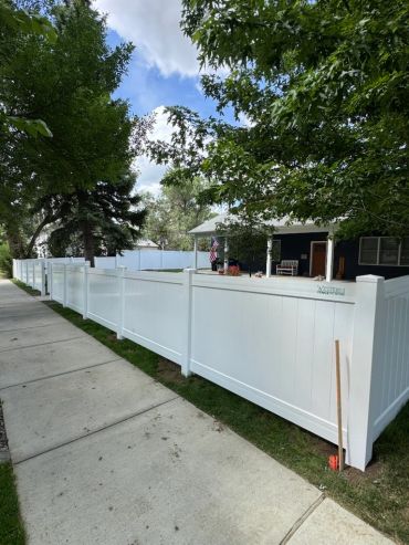 White vinyl fence along a sidewalk near a house.