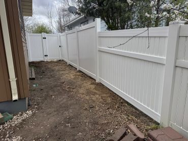 Newly installed white vinyl privacy fence in backyard.