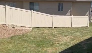 A white fence with a sloping installation next to a house.