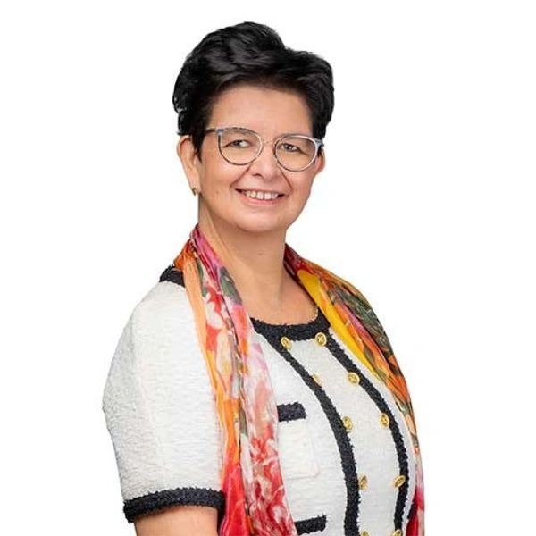 Smiling woman with short hair, glasses, and a colorful scarf.
