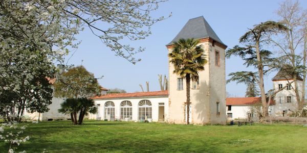 Historic building with stone tower and surrounding green lawn under clear sky.
