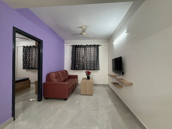 Modern living room with purple accent wall and brown sofa.