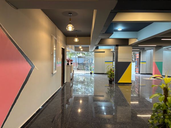 Modern corridor with glossy floors, colorful geometric wall designs, and hanging lights.