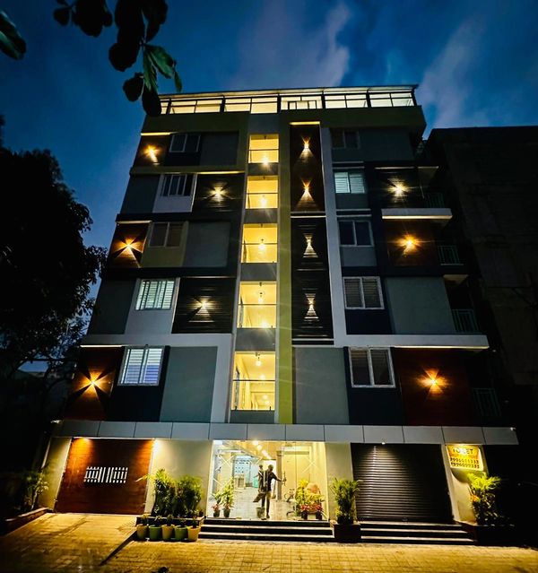 Modern apartment building illuminated at night with warm lights.