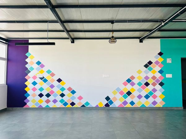 Colorful diamond pattern mural on a white wall with purple and teal accents.