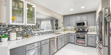 Modern kitchen with gray cabinets and stainless steel appliances.