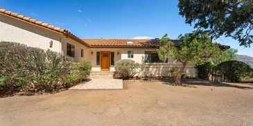 Front view of a single-story house with desert landscaping.