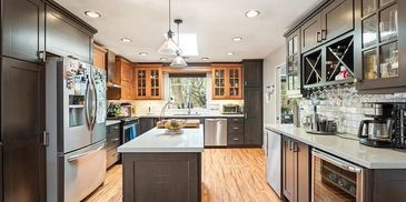 Modern kitchen with dark cabinets and wooden floor.