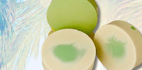 Three round soaps with green and white colors on a light background.