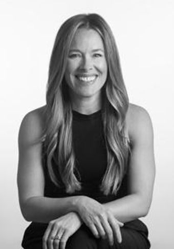 Smiling woman with long hair in a sleeveless top sitting calmly.