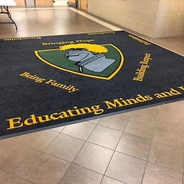 School entrance mat with a knight emblem and motivational phrases.