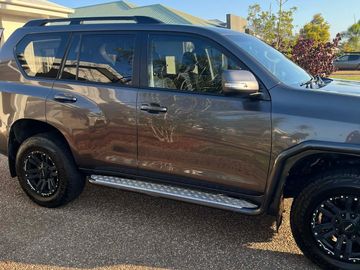 Side view of a dark gray SUV with black wheels parked outdoors.