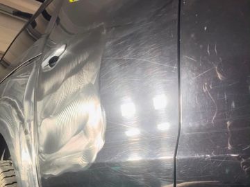 Heavy swirl marks and paint defects visible under inspection lighting before paint correction