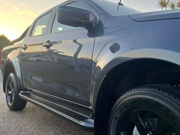 Close-up view of a black pickup truck's side during sunset.