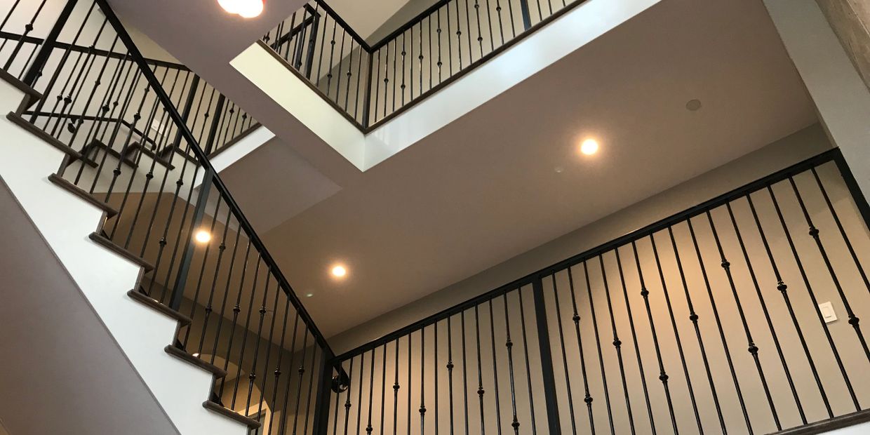 Modern staircase with black metal railings and recessed ceiling lights.