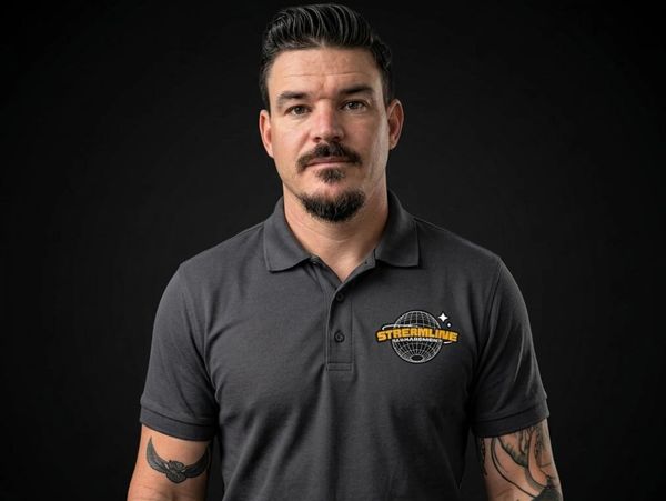 Man with tattoos wearing a gray polo shirt with a logo.