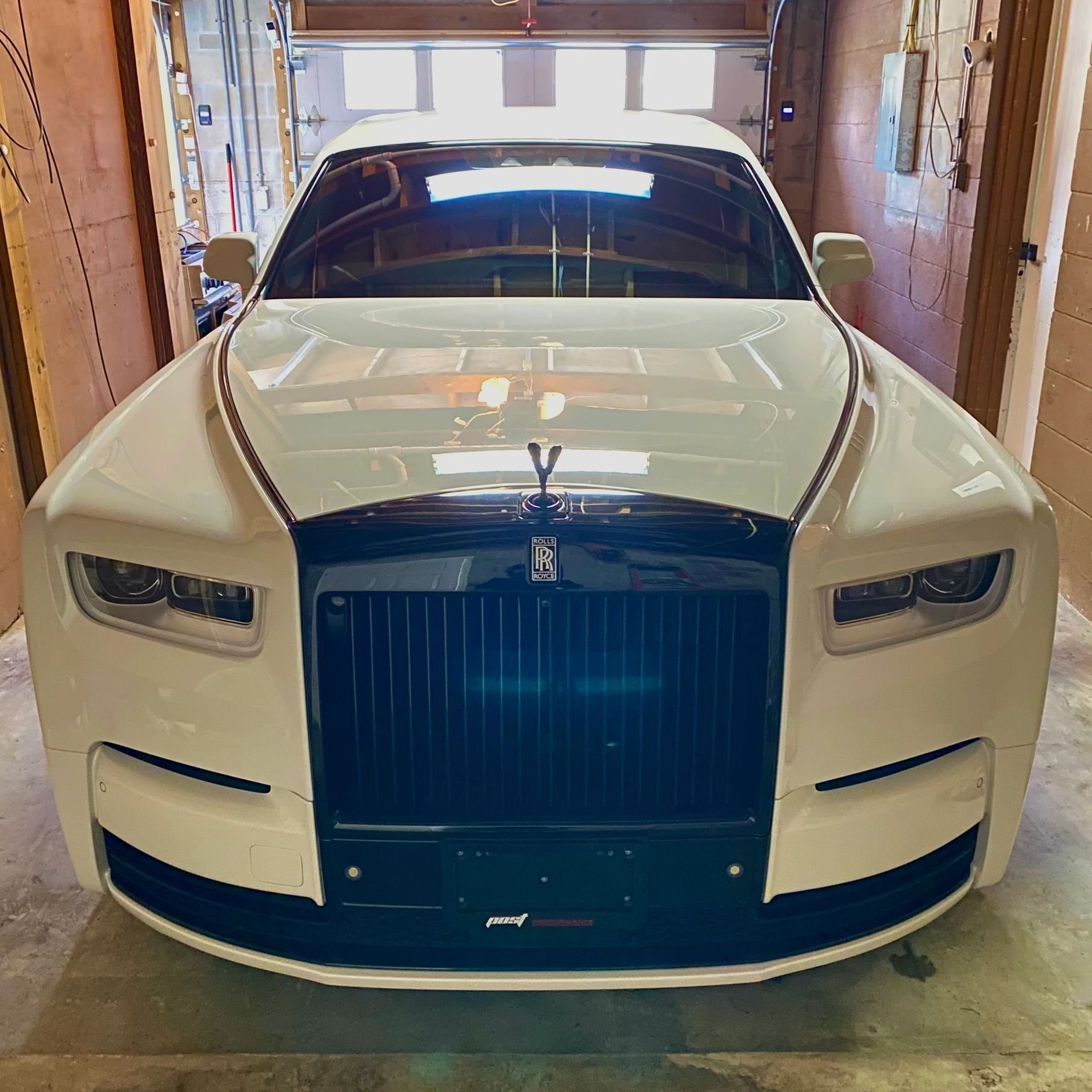 Front view of a white Rolls-Royce parked in a garage.