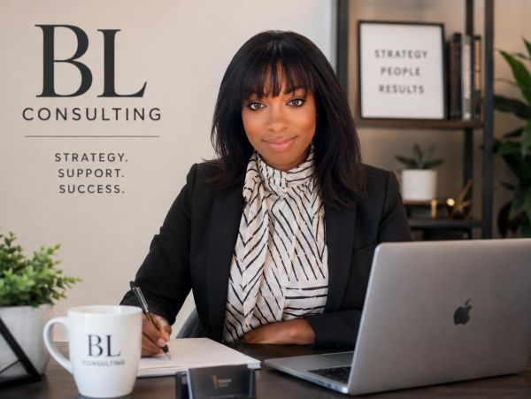 Professional woman at desk with BL Consulting branding, ready to assist.