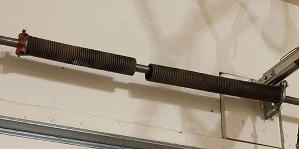 Close-up of a garage door torsion spring system mounted above the door.
