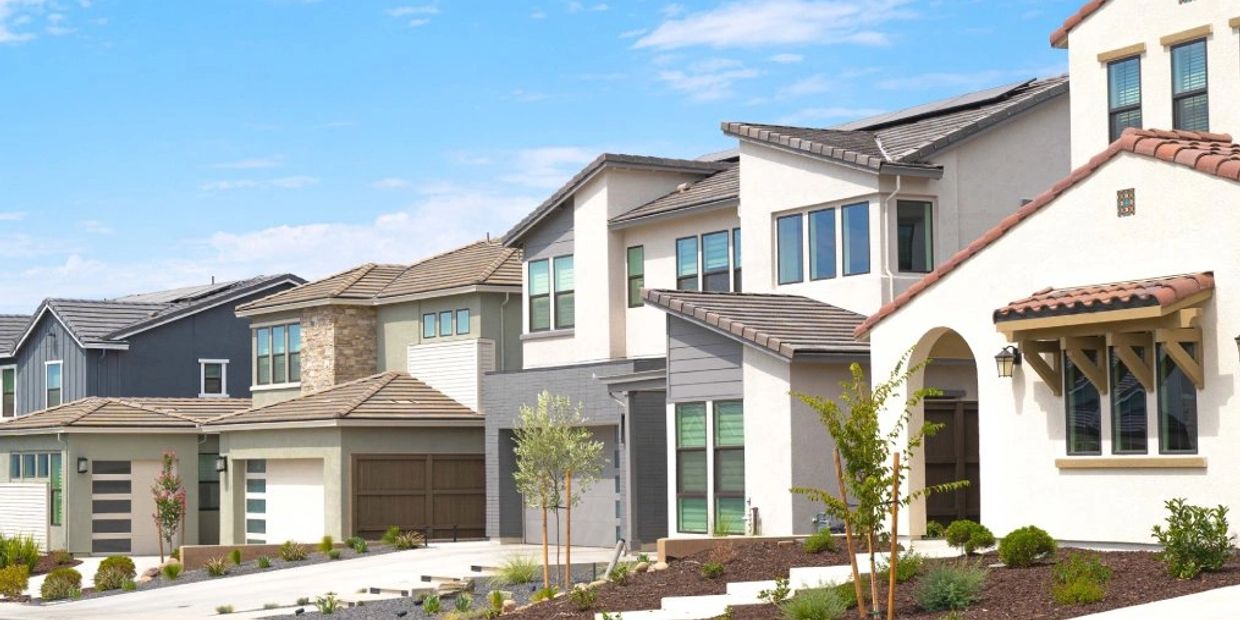 Row of modern suburban houses with varied designs under a clear blue sky.