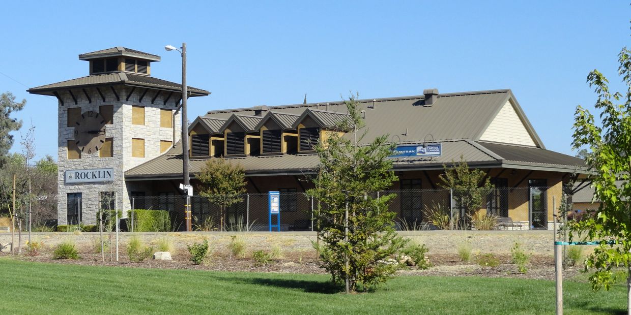 Rocklin train station with a clock tower under clear blue sky.