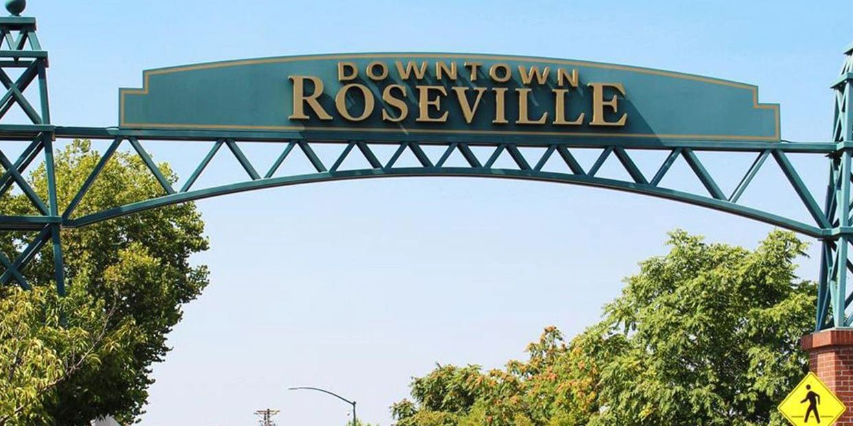 Entrance arch sign reading 'Downtown Roseville' with trees around.