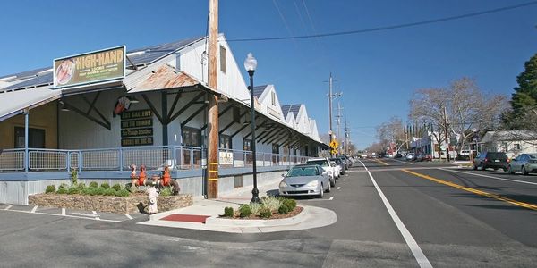 A street view with parked cars and a warehouse building under clear blue sky.
