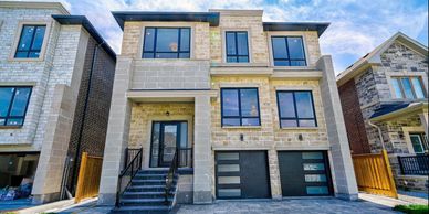 Modern two-story house with a stone facade and large windows.