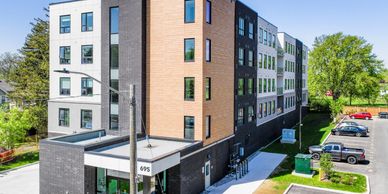 Modern four-story apartment building with mixed brick and wood facade.