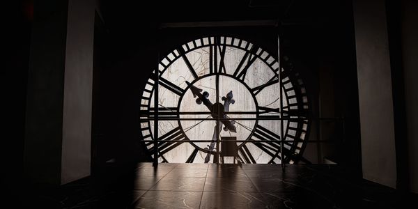 Silhouette of a person standing inside a large clock tower with Roman numerals.
