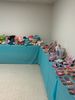 Rows of colorful plush toys neatly arranged on turquoise shelves.
