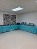 A room corner with turquoise cushioned seating and a collage on the wall.