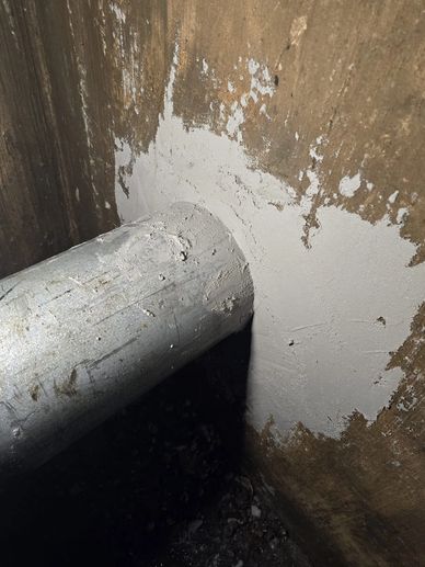 Pipe protruding through a patched wall.