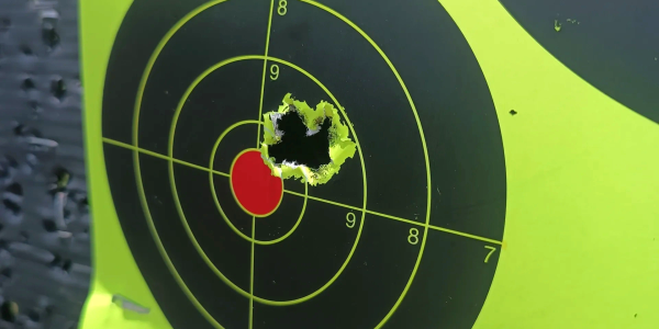 Close-up of a shooting target with a cluster of bullet holes near the bullseye.