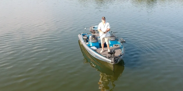 A man fishing alone on a small boat in calm water.