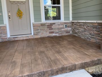 Empty porch with wood-style flooring and stone walls.