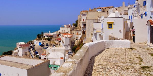 Coastal town with white buildings overlooking the sea under a clear blue sky.