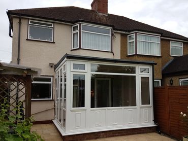 A white conservatory attached to a semi-detached house.
