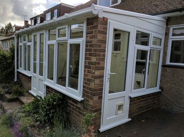 A brick sunroom with white-framed windows and door.