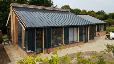 Modern house with large glass windows and metal roof.