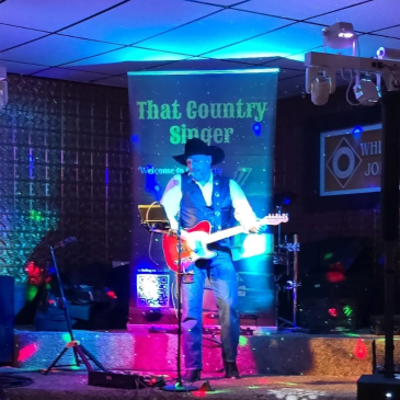 Country singer performing live on stage with guitar.