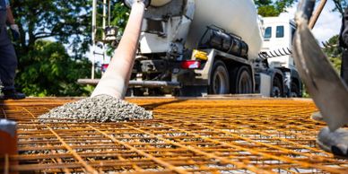 Concrete pouring over steel reinforcement at a construction site.