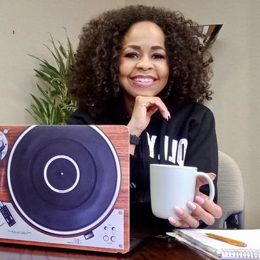 Smiling woman with curly hair holding a white mug.
