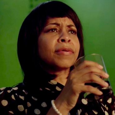 Woman holding a glass with a serious expression.