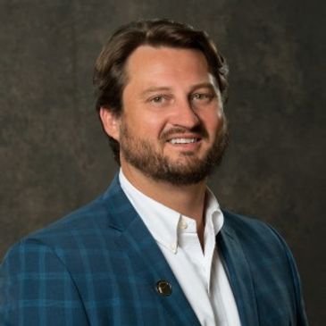 Man in a blue checkered blazer smiling